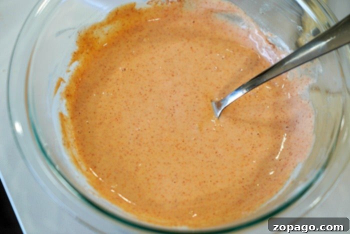 Zesty Buffalo Cauliflower Sauce Close-up of vibrant orange buffalo cauliflower sauce, ready for coating.