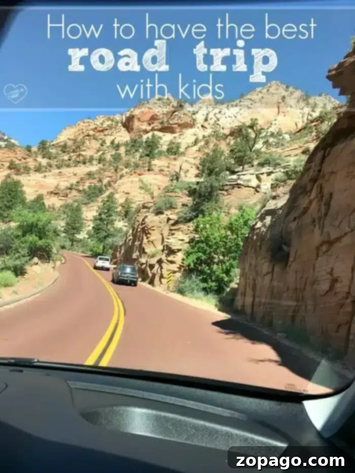 Expert Tips for the Best Road Trip Games for Kids and Family Fun. A scenic view from a car dashboard window, showing a winding road through rocky, mountainous terrain under a clear blue sky, with two cars ahead. Overlay text reads, "How to have the best road trip with kids."