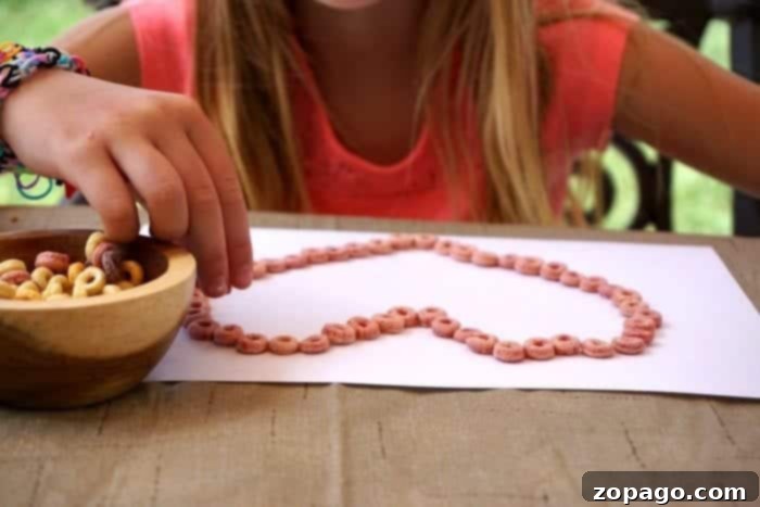 Create Your Own Edible Sand 3 Child creating Cheerios craft, gluing cereal onto paper.