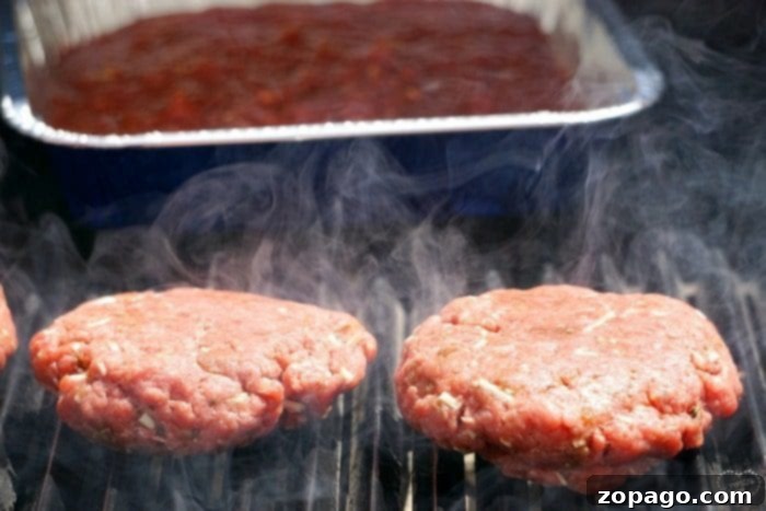 Burgerizza 5 Two burger patties sizzle on a hot grill, emitting smoky aromas, reminiscent of a delicious New York pizza's char, with rising smoke enhancing the cooking atmosphere.