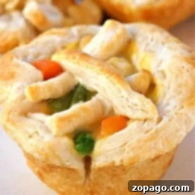 A mini chicken pot pie muffin with a flaky crust, topped with carrots, peas, and a lattice of dough strips.