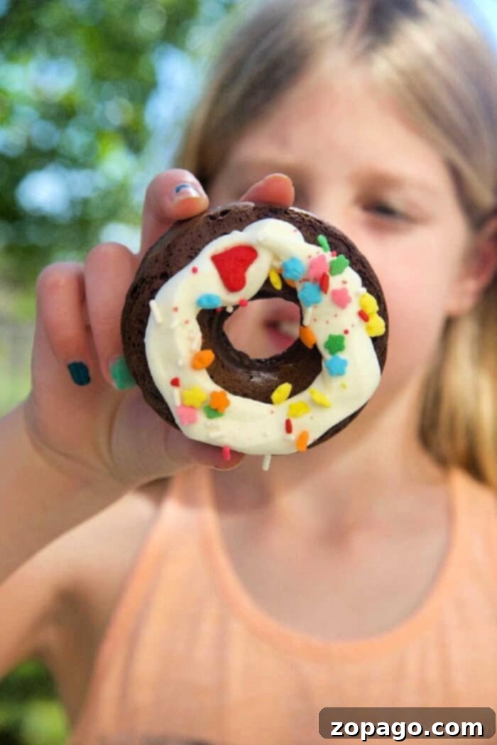Cake mix donuts are so easy to make using any flavor of boxed cake mix you want! It's an easy baking project with your kids. #cakemix #donuts #doughnuts #dessert #bakingwithkids #dessert #breakfast Delicious chocolate cake mix donuts topped with glaze and sprinkles, fresh from the oven, an easy baking project with kids.