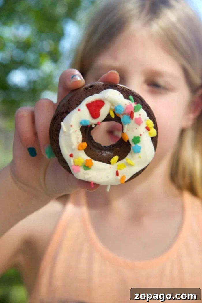 Cake mix donuts are so easy to make using any flavor of boxed cake mix you want! It's an easy baking project with your kids and a fun way to make baked donuts right at home with a few ingredients. Load them up with fun toppings for breakfast or dessert. #cakemix #donuts #doughnuts #dessert An array of beautifully decorated cake mix donuts, some with chocolate glaze and sprinkles, others with white icing, showcasing diverse and appealing homemade options.