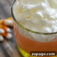 Overhead shot of a single candy corn parfait glass, with scattered candy corn around, emphasizing its vibrant appeal as an easy Halloween dessert.