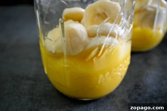 Easy Orange Creamsicle Drink: A creamy, frosty Orange Julius copycat layered with fresh citrus flavor. Two mason jars filled with a layered orange creamsicle drink, topped with whipped cream and a sprinkle of cinnamon.