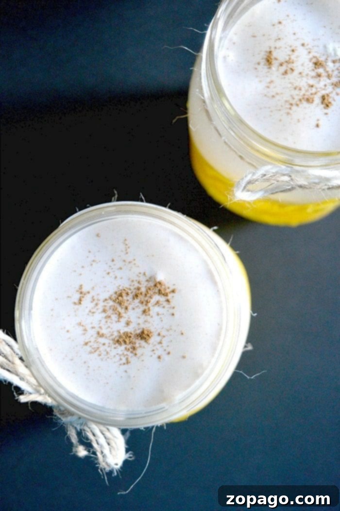Refreshing Non-Alcoholic Orange Creamsicle Drink: A simple and creamy Orange Julius copycat recipe. A vibrant non-alcoholic orange creamsicle drink in a mason jar, garnished with a ripe banana slice and a straw, on a rustic wooden surface.