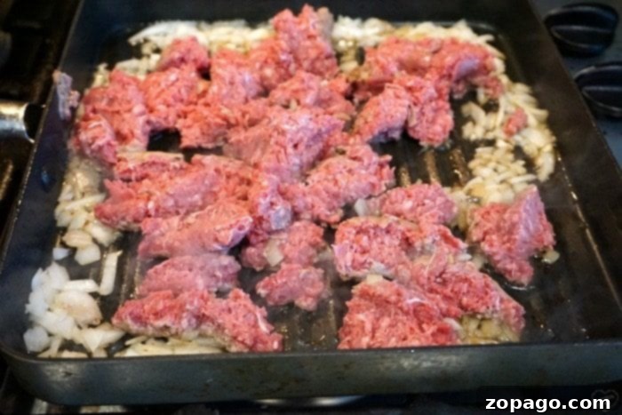 Close up of ground beef and diced onions cooking in a skillet