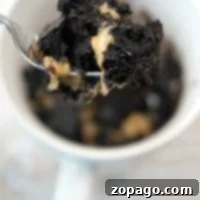 Indulgent Mug Brownie 6 A spoonful of chocolate and peanut butter brownie being lifted from a mug offers a delightful twist on how to make a brownie in a mug.