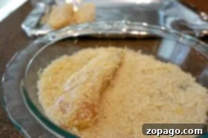Crispy Baked Fish 7 Raw fish being coated in breadcrumbs in a glass dish, with a tray lined with foil in the background—perfect preparation for oven fried fish or chicken dinners.
