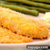 Close-up of a serving of crispy oven-fried fish fillets with a side of green beans and lemon