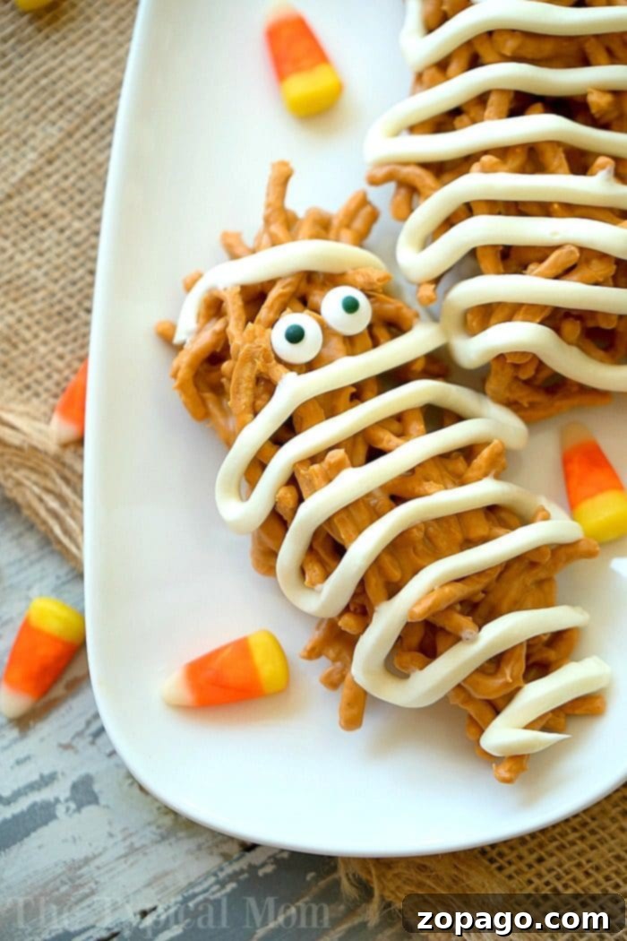 These mummy haystacks are so cute and an easy no bake dessert to make! The perfect peanut butter Halloween treat that your kids can help you make too. #halloween #mummy #haystacks #peanutbutter #dessert #butterscotch Finished Halloween Mummy Haystacks with candy eyes and white frosting bandages arranged on a platter
