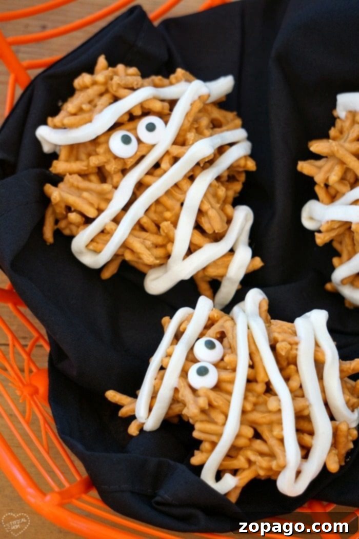 These mummy haystacks are so cute and an easy no bake dessert to make! The perfect peanut butter Halloween treat that your kids can help you make too. #halloween #mummy #haystacks #peanutbutter #dessert #butterscotch Mummy Haystacks with candy eyes and frosting bandages arranged on parchment paper