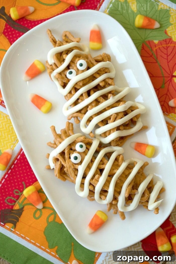 Mummy haystacks are so cute and an easy no bake dessert to make! The perfect peanut butter Halloween treat that your kids can help you make too. #halloween #mummy #haystacks #peanutbutter #dessert #butterscotch Close-up of final Halloween mummy haystacks ready to eat on a white plate
