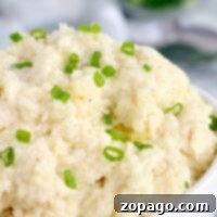 A bowl of slow cooker mashed potatoes topped with chopped green onions.