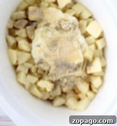 Creamy Slow Cooker Mashed Potatoes 5 Diced potatoes with butter, sour cream, and seasonings in a white slow cooker, ready to be mashed.
