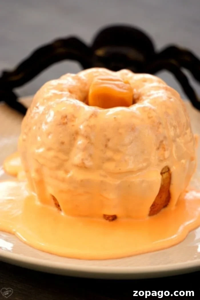 Easy Pumpkin Bundtlets 7 Two completed pumpkin bundt cakes with frosting and caramel stems on a white plate.
