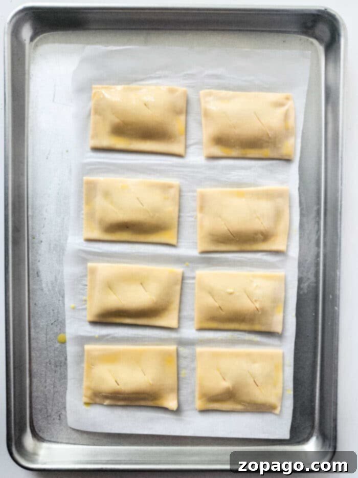 Freshly baked pumpkin turnovers with a golden crust, dusted with powdered sugar.