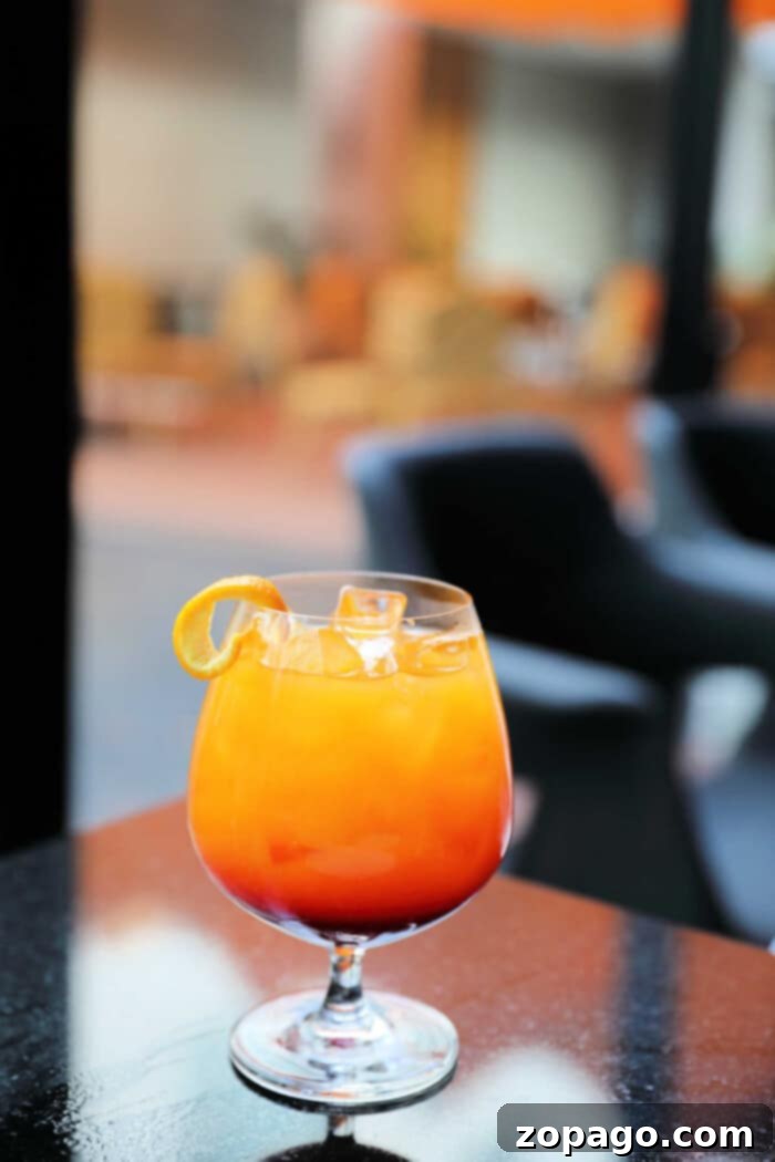 Sparkling Island cocktail is what to call this favorite pineapple drink of mine! Goes perfectly with any meal really and easy to create with rum and pineapple juice. Cocktail or mocktail directions. #pineapple #cocktail #drink #mocktail #punch A vibrant sparkling island cocktail with a citrus twist sits on a reflective table in a stylish, blurred background setting. Its golden hue and effervescence promise a refreshing experience.