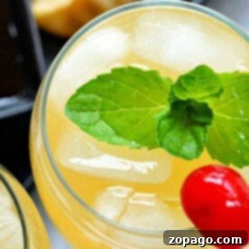 Pineapple Paradise Rum 3 Close-up of a sparkling island cocktail with ice, a mint garnish, and a cherry on top.