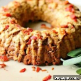 Mastering Stuffing in a Bundt Pan 3 A savory bundt cake with herbs and bacon pieces on a beige plate, garnished with fresh sage leaves, showcases how to cook stuffing in a bundt pan, elevating this classic dish to new heights.
