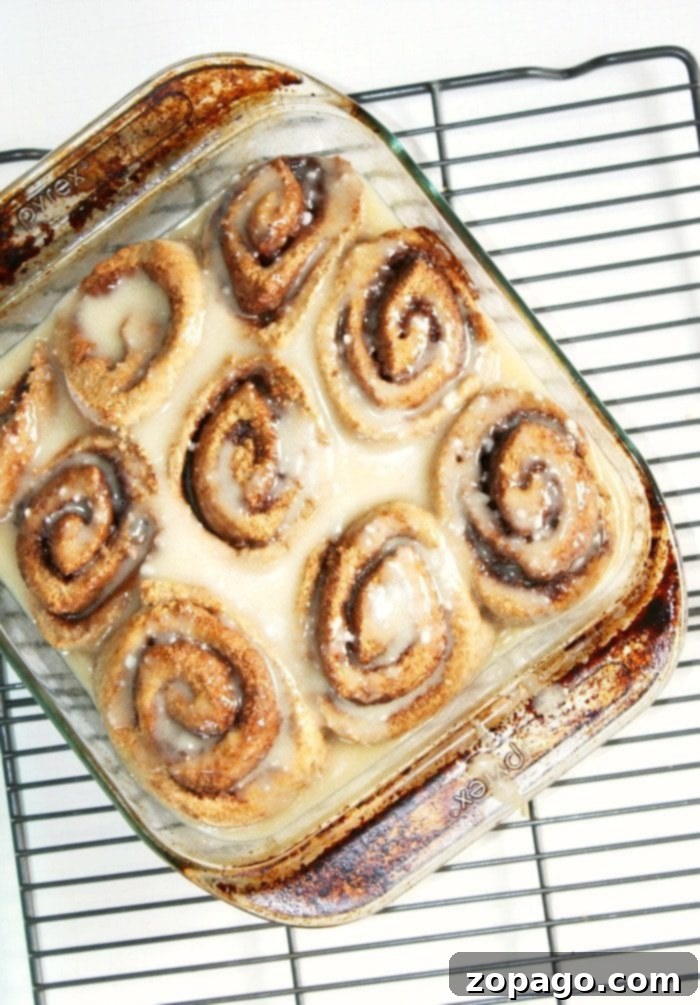 Gingerbread Cinnamon Rolls - Delicious Holiday Breakfast Baked gingerbread cinnamon rolls with white icing in a baking pan, ready to be served.