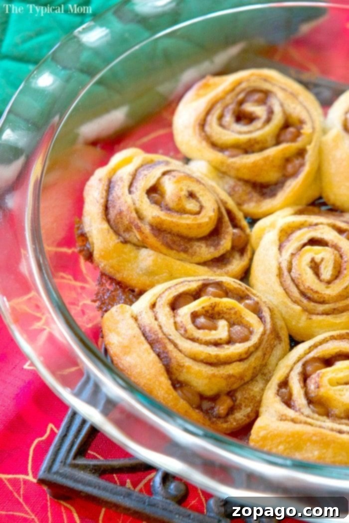 Crescent roll cinnamon rolls sit elegantly in a glass dish atop a vibrant red tablecloth.