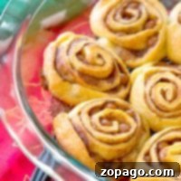 Crescent roll cinnamon rolls sit elegantly in a glass dish atop a vibrant red tablecloth.