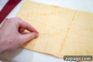 A hand pinching perforations on crescent rolls dough