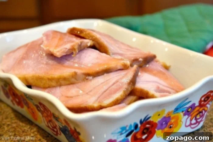 Bake the Perfect Ham 3 Sliced baked ham on a platter with a serving fork, ready for a holiday meal.