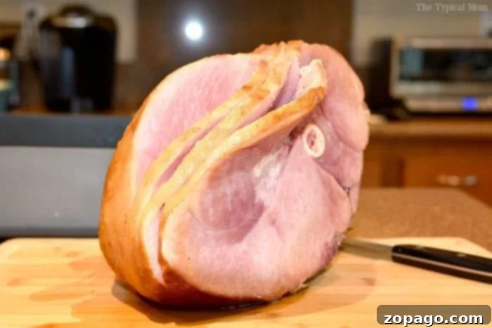 Baked ham glaze recipe with orange juice, brown sugar, and honey is incredibly simple and makes your ham taste amazing!! Just 3 ingredients, you've got to try this ham glaze next time. #ham #glaze #orangejuice #baked #holidays Close-up of a glazed ham showcasing its beautiful golden-brown crust and sticky texture.