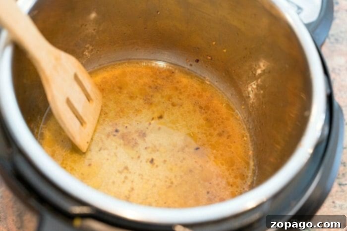 Effectively remove burnt food from your Instant Pot with a plastic scraper, preventing damage and making cleaning easier. Essential tips for Instant Pot maintenance. A person gently scraping burnt food from the bottom of an Instant Pot inner pot using a plastic spatula to avoid scratches.