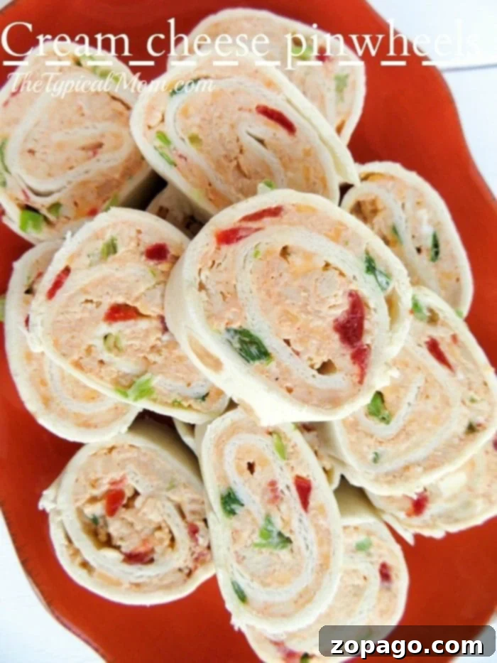 Cream cheese pinwheels are a must-try appetizer for any event, bursting with incredible flavor. A vibrant orange platter holds an array of appetizing cream cheese pinwheels, garnished with colorful bell peppers.
