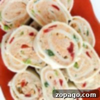 A vibrant orange dish showcases a plate of cream cheese pinwheels, bursting with the colorful crunch of red and green bell peppers.