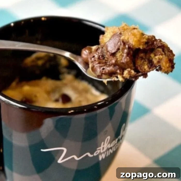 Chocolate Chip Mug Cookie 2 A spoonful of irresistible chocolate chip cookie in a mug, showcasing its gooey, egg-free goodness, promising comfort in every bite.