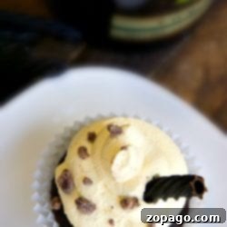 Baileys and cream cupcakes adorned with silky cream frosting, scattered chocolate bits, and an elegant chocolate curl.