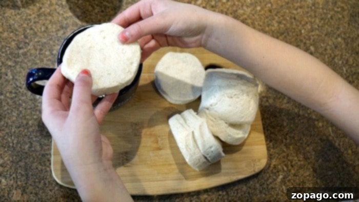 How to make pizza in a mug! Just 2 minutes in your microwave and you can have a little personal pizza that's cheesy and filled with your favorite toppings. A great after school snack that kids can make on their own and a fun 'baking' project you can do with little ones. We love easy mug recipes. #pizza #mug #quick #personal #microwave #fast Hands holding biscuit dough over a cutting board with more dough pieces—imagine the same simplicity applied to creating pizza in a mug, transforming basic ingredients into something delightfully unexpected and easy.