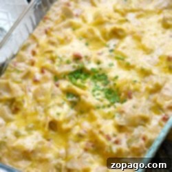 A cheesy chicken tortilla bake topped with chopped green herbs in a glass baking dish.