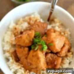 A bowl of rice topped with savory instant pot teriyaki chicken pieces and a sprinkle of chopped green onions.