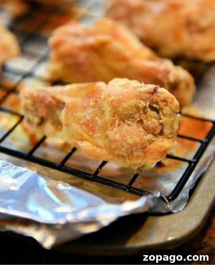 The secret to incredibly crispy oven baked chicken wings revealed. Close-up of golden, perfectly crispy chicken wings on a wire rack, illustrating the success of the baking technique.