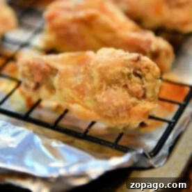 Ultimate Crispy Chicken Wings: Baking Perfection at 425 8 Close-up of irresistible, crispy chicken wings baked to perfection on a cooling rack with foil underneath.