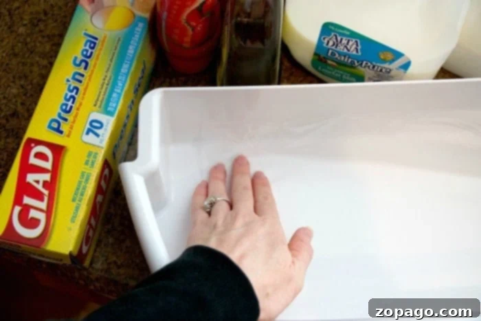 Your Simple Refrigerator Refresh Guide 2 Close-up image demonstrating how to clean your fridge shelves using a spray cleaner and paper towel, highlighting effective cleaning techniques.