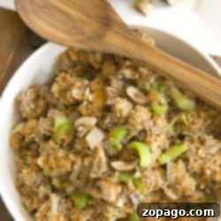 Savory Pepperidge Farm Sausage Stuffing 3 A bowl of Pepperidge Farm Sausage Stuffing with mushrooms, celery, and bread crumbs, topped with a wooden spoon, showcasing its rich, savory appeal.