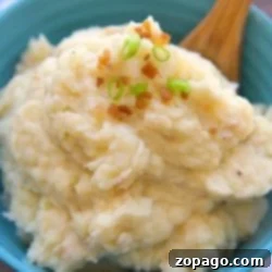 A bowl of pressure cooker mashed potatoes topped with chopped green onions and bacon bits, accompanied by a wooden spoon.