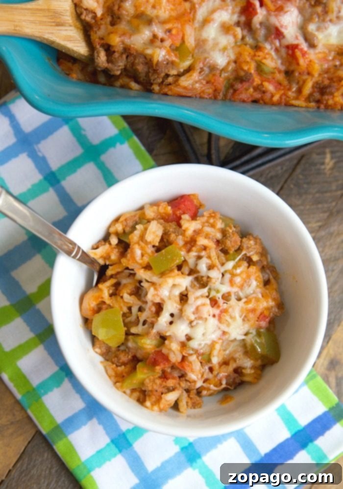 This cheesy stuffed pepper casserole is a family favorite for sure! Like deconstructed stuffed bell peppers it's an easy casserole topped with lots of cheese you can throw together and even my kids love it! Packed with the classic flavors you remember it is easier to make and great the next day too. #stuffed #pepper #peppers #casserole #easy #dinner #groundbeef #unstuffed #rice #green Stuffed Pepper Casserole with melted cheese and rice