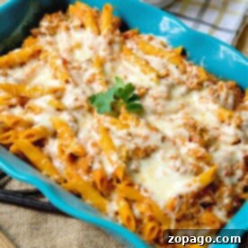 A lazy lasagna casserole with baked pasta, melted cheese, and ground meat in a blue dish, garnished with parsley.