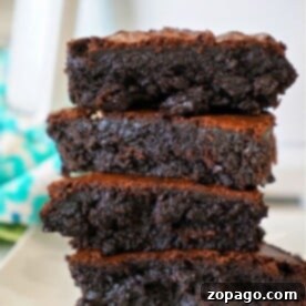 A stack of four gooey chocolate brownies made from cake mix sits enticingly on a white plate, set against a blurred turquoise background.
