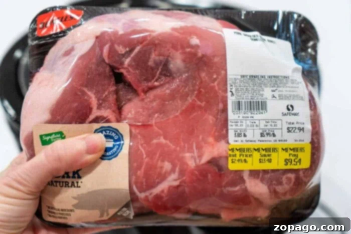 Fork-Tender Instant Pot Pork Shoulder 2 A hand holds a packaged pork shoulder roast, ideal for an Instant Pot pulled pork recipe.