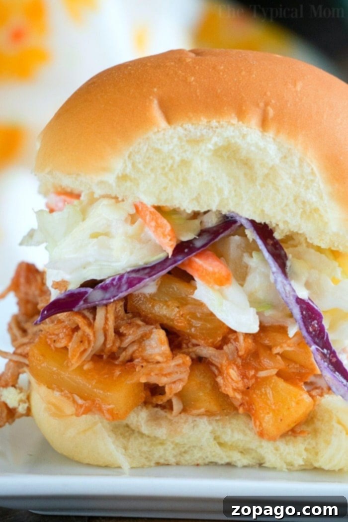 Delicious Instant Pot pulled pork sandwich with BBQ sauce and coleslaw. A close-up of an Instant Pot Hawaiian pulled pork sandwich with pineapple and coleslaw.
