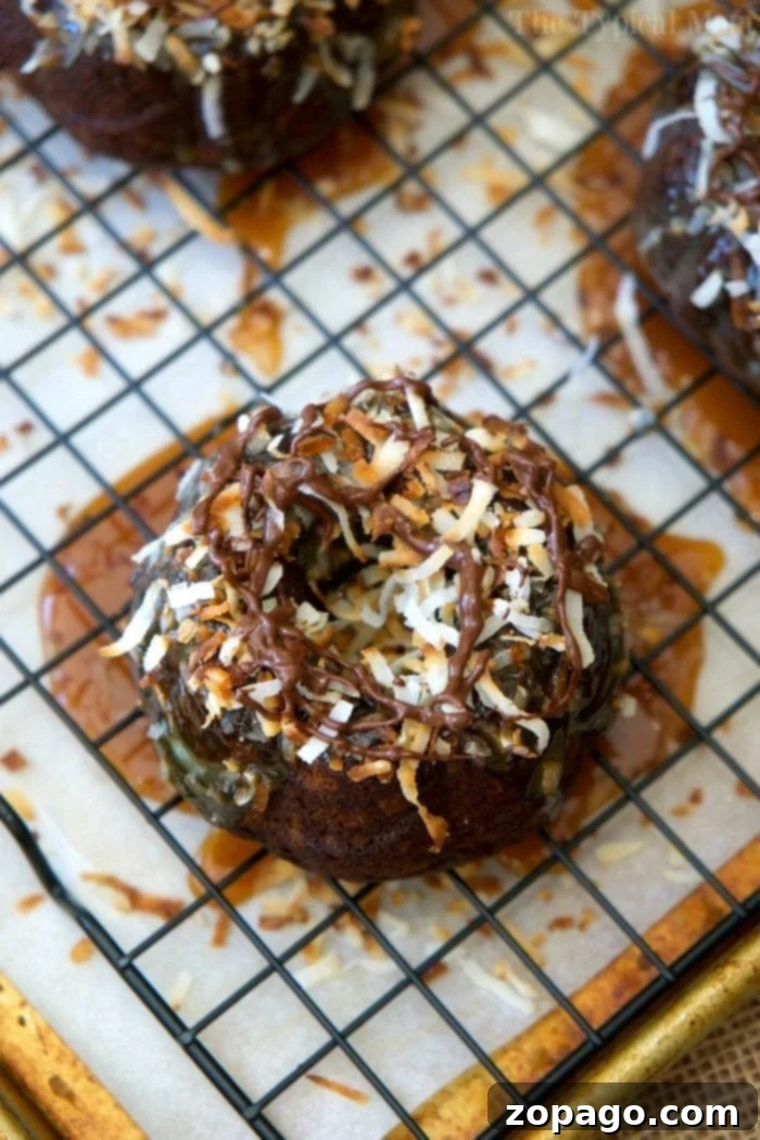 This easy 5 ingredient Samoa cake recipe is amazing! Make into a bundt or mini bundts, covered in caramel, coconut, and chocolate for a slice of heaven. Delicious Samoa mini bundt cakes topped with caramel, coconut, and chocolate drizzle, showcasing their beautiful individual shape.