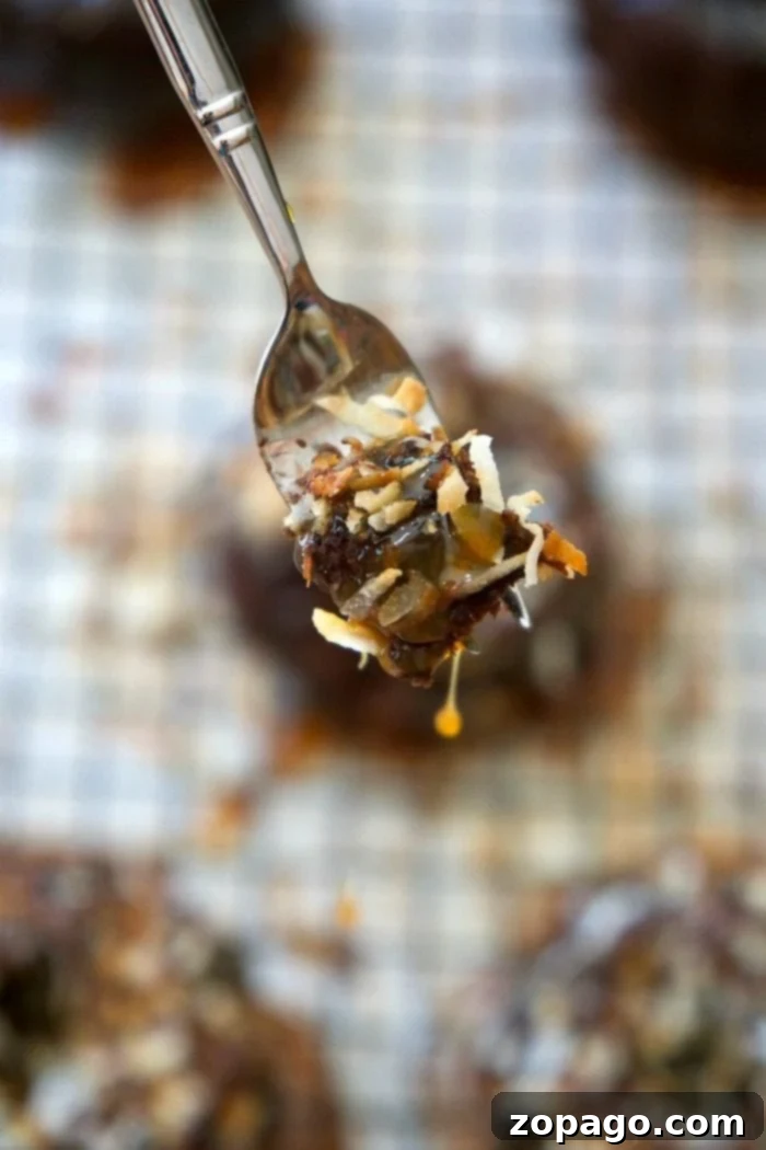 This easy 5 ingredient Samoa cake recipe is amazing! Make into a bundt or mini bundts, covered in caramel, coconut, and chocolate for a slice of heaven. Three beautifully decorated Samoa mini bundt cakes arranged on a wooden board, showcasing their rich caramel, toasted coconut, and chocolate drizzles.